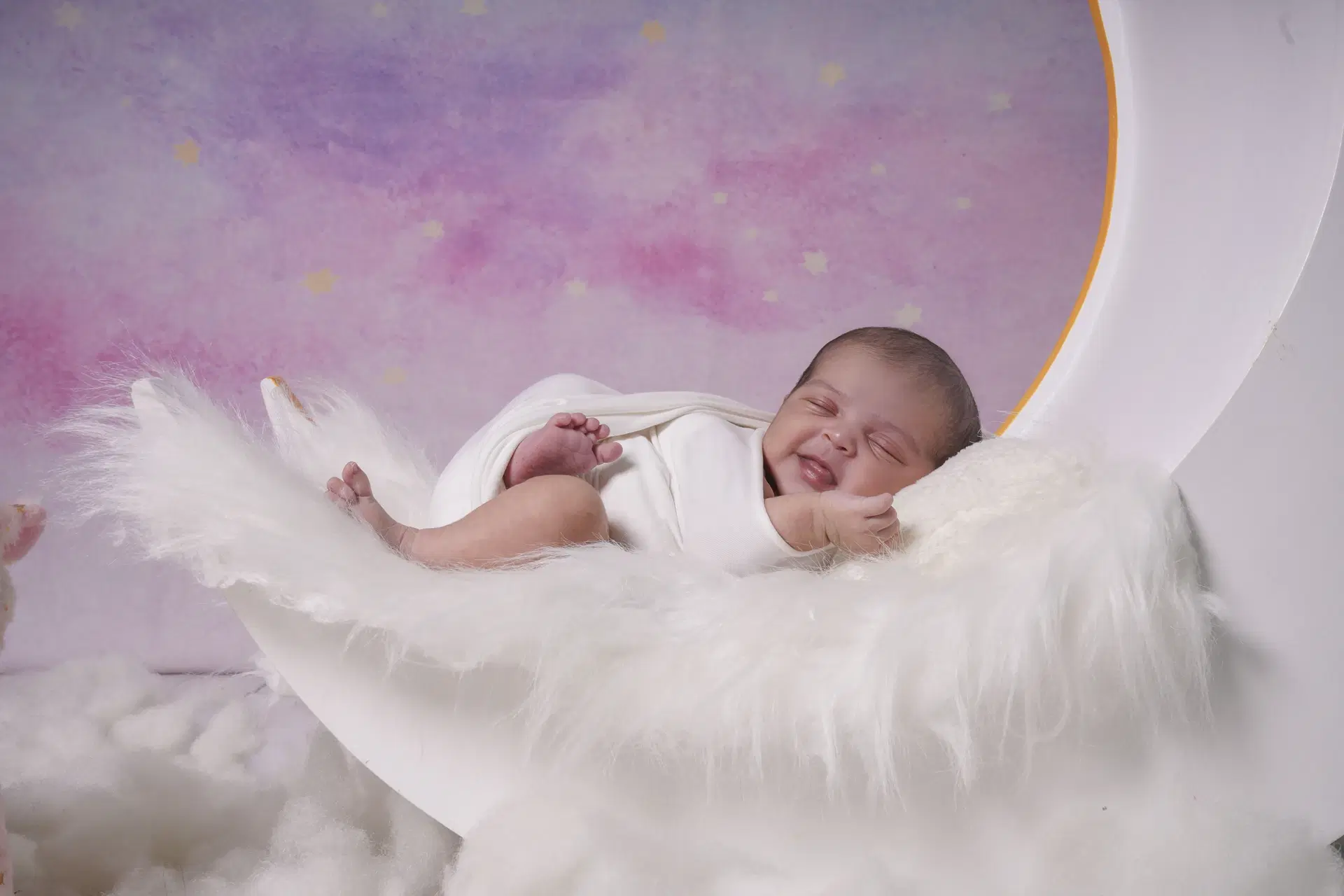 Smiling newborn resting on crescent moon prop